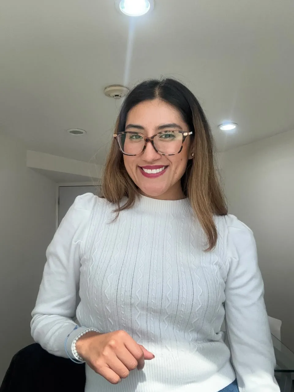 Geraldine Ramírez, nutrióloga, sonriendo con lentes y suéter blanco.